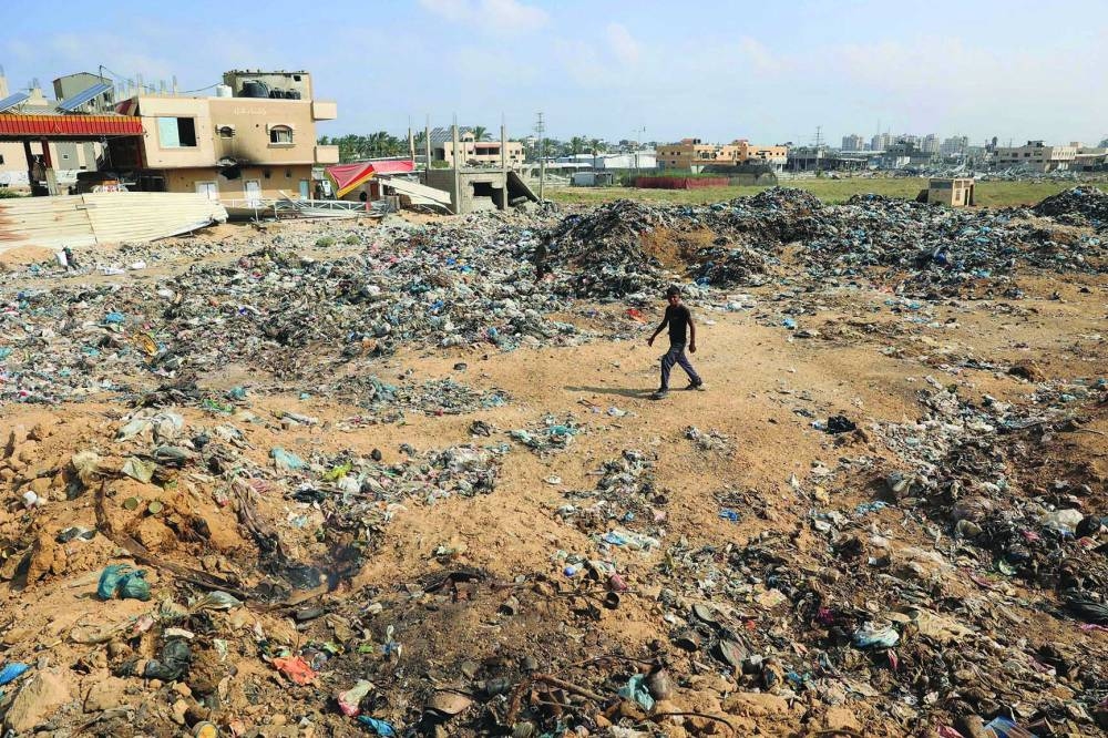 A Palestinian walks past piles of waste, as garbage collection and many other municipality services come to a halt due to the Israeli bombardment of the Gaza Strip, at the Al-Maghazi Palestinian refugee camp, in the central Gaza Strip.