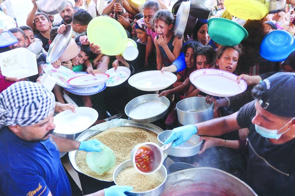 
Displaced Palestinians wait to receive for food at a food distribution point, in Beit Lahia, in the northern Gaza Strip yesterday. 