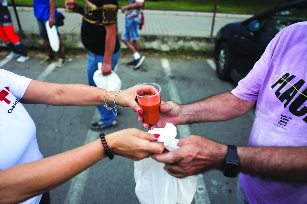 A volunteer gives cold gazpacho and a bag with food to a man during a food and cold drink distribution campaign for people in need and homeless, to beat the heat on a hot summer night, during hot weather in Cordoba, Spain. – Reuters