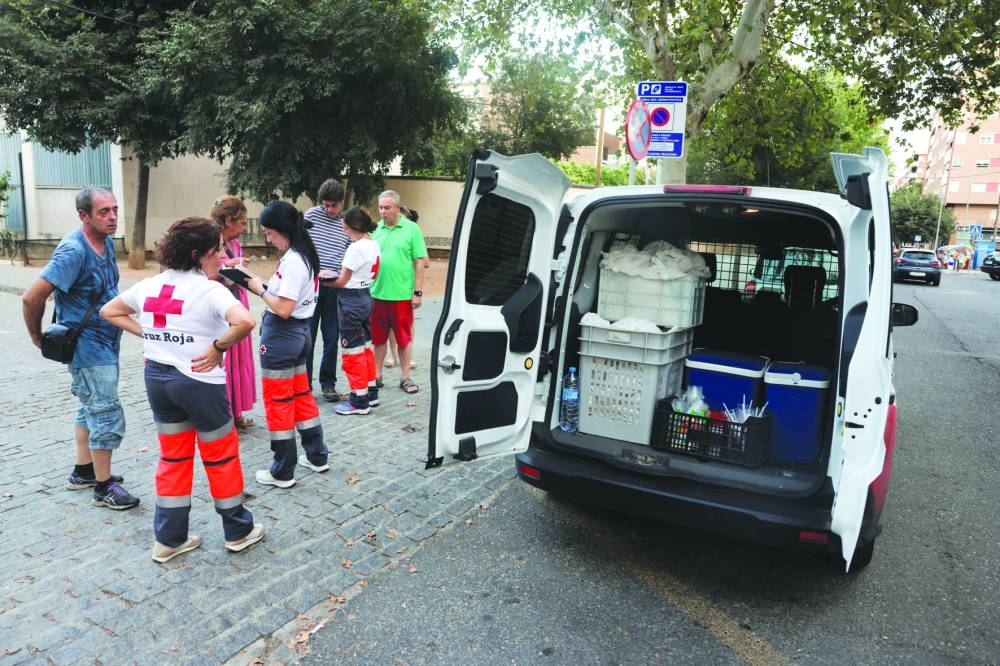 
Volunteers Emilia Leon, 57, her daughter Elena Porcel, 31, and Angeles Urbano, 31, talk with a group of persons during a food and cold drink distribution campaign for people in need and homeless, in Cordoba, Spain. – Reuters 