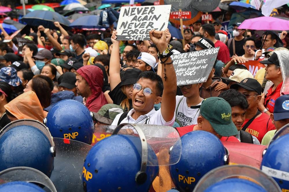 A protester holds a placard as their march to congress is blocked by police during a demonstration coinciding with Philippine President Ferdinand Marcos’ State of the Nation Address, in Manila, yesterday.