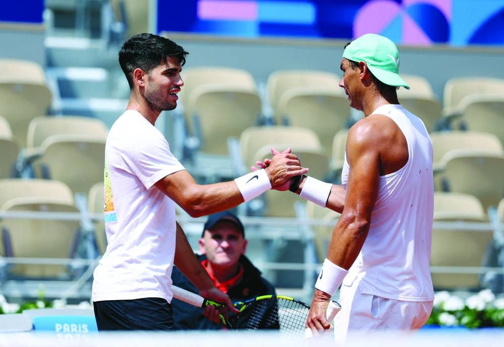 Carlos Alcaraz (left) of Spain shakes hands with Rafael Nadal during training at Roland Garros Stadium, Paris, France, on Wednesday. (Reuters)