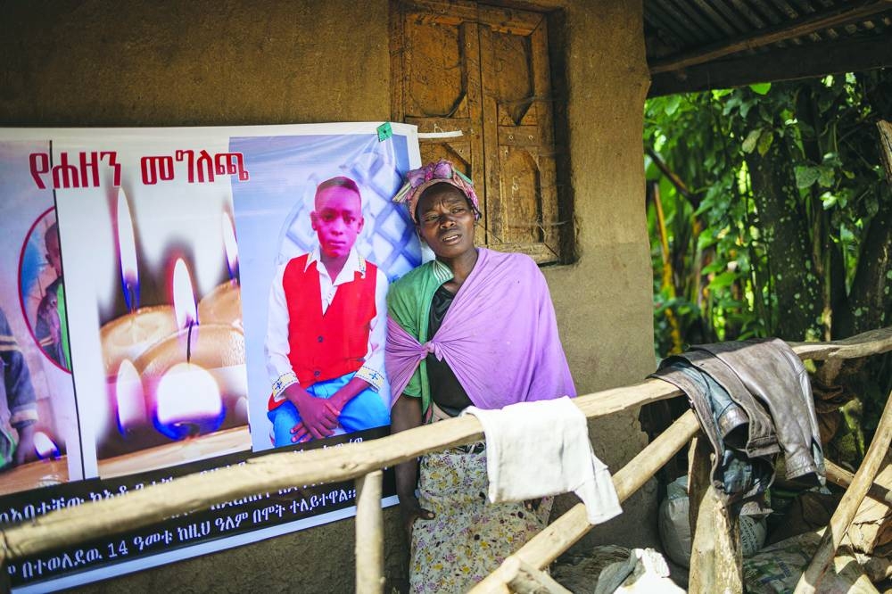 A woman leans against a commemorative poster of a family member perished during a nearby landslide in Kencho Shacha Gozdi.