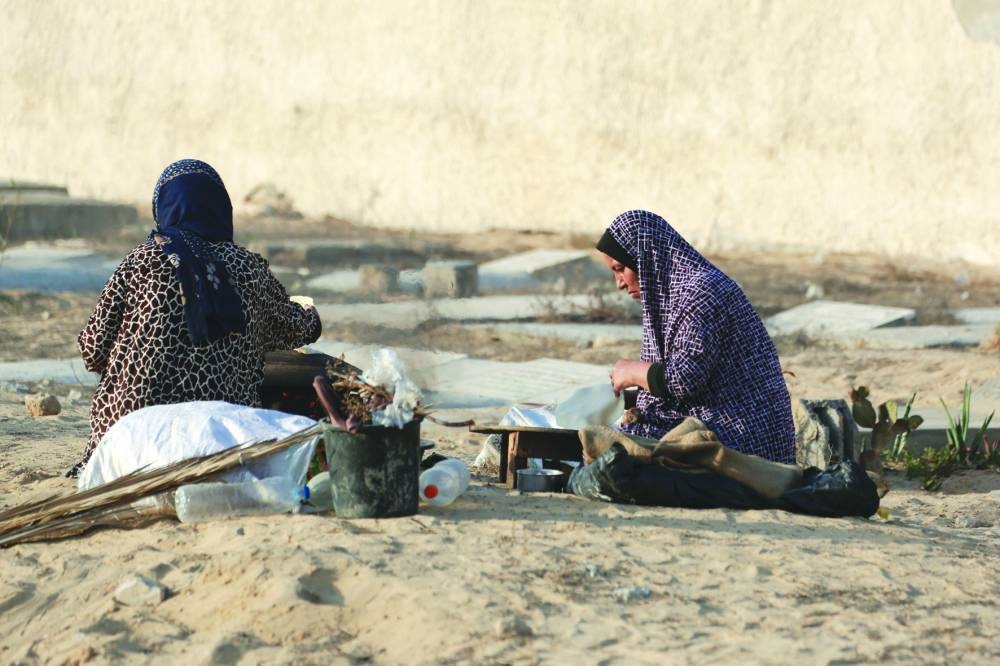
Displaced Palestinians from the eastern part of Khan Yunis, prepare to cook bread at a temporary camp set up in the grounds of a cemetery in the western part of the city, in the southern Gaza Strip, yesterday. 