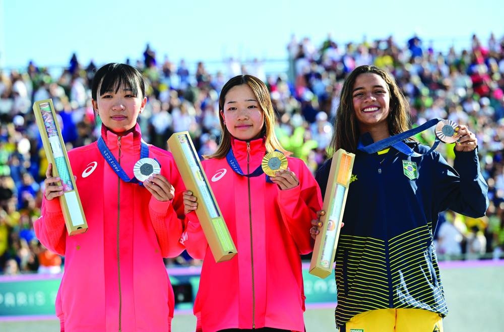 Gold medallist Coco Yoshizawa of Japan celebrates on the podium with silver medallist Liz Akama of Japan and bronze medallist Rayssa Leal of Brazil in Paris yesterday. (Reuters)