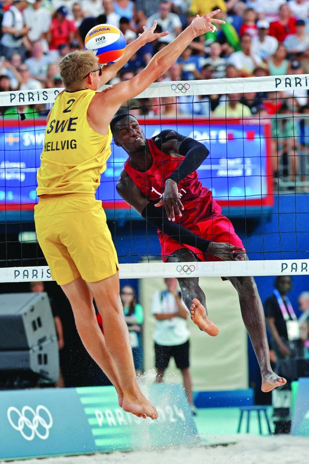 Qatar’s Cherif Younousse spikes the ball as Sweden’s Jonatan Hellvig attempts a block during the pool A beach volleyball match at the Paris Olympic Games on Monday. (AFP) 