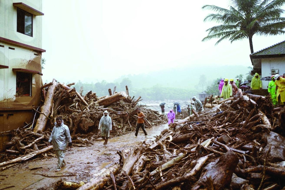 
People walk past debris at a landslide site in Wayanad, yesterday. (Reuters) 