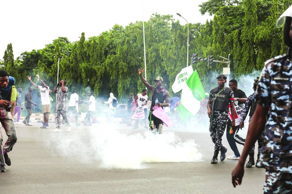 Demonstrators react as Nigerian policemen fire tear gas canisters during the End Bad Governance protest in Abuja on Thursday. 