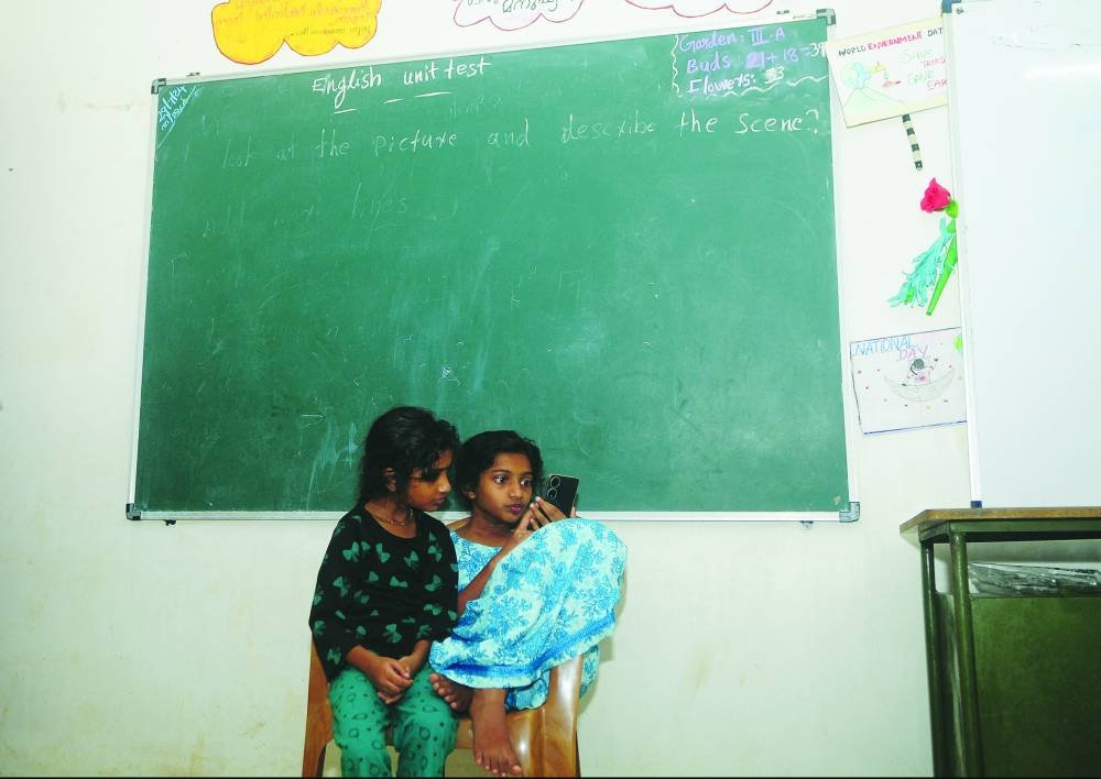Girls who lost their homes in landslides, look at a mobile phone as they sit in a classroom at a school, which has been converted into a temporary relief camp, in Meppadi village in Wayanad, India, yesterday. 