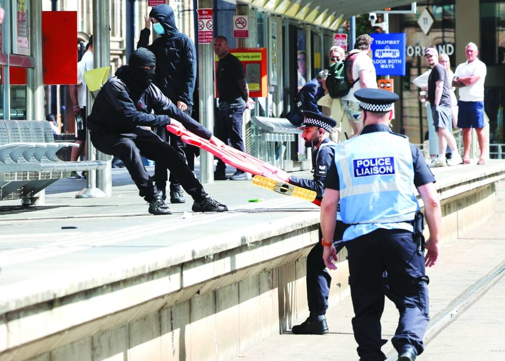 A police officer tries to stop an anti-immigration demonstrator from throwing a barrier during a protest in Manchester.