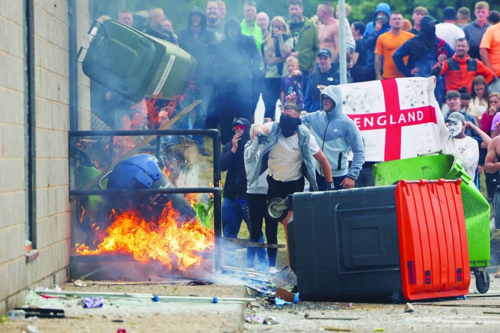 Protestors throw a garbage bin on fire outside a hotel in Rotherham, Britain, yesterday.