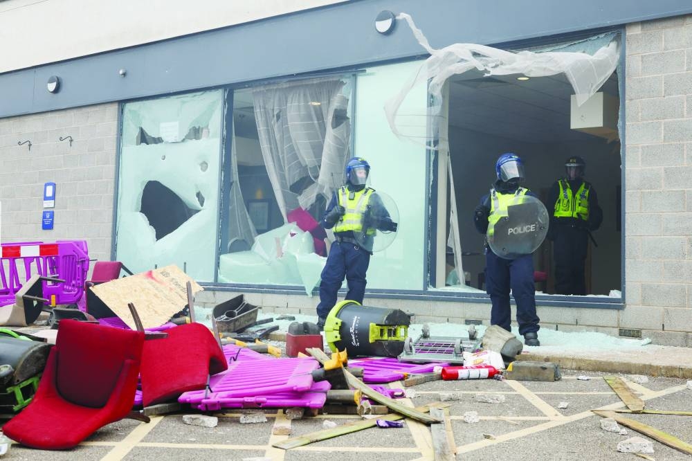 
Police officers stand near the broken windows of the hotel during an anti-immigration protest, in Rotherham, Britain, yesterday. 