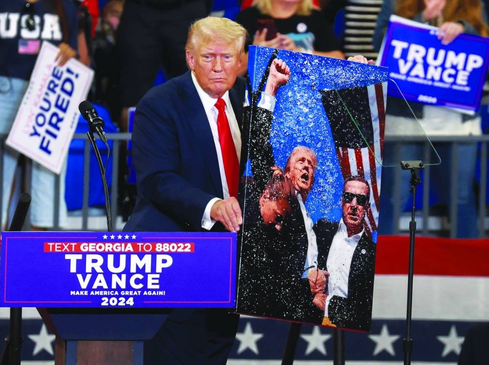 Trump holds artwork that he autographed for the artist, depicting the former president during the assassination attempt last month. – AFP