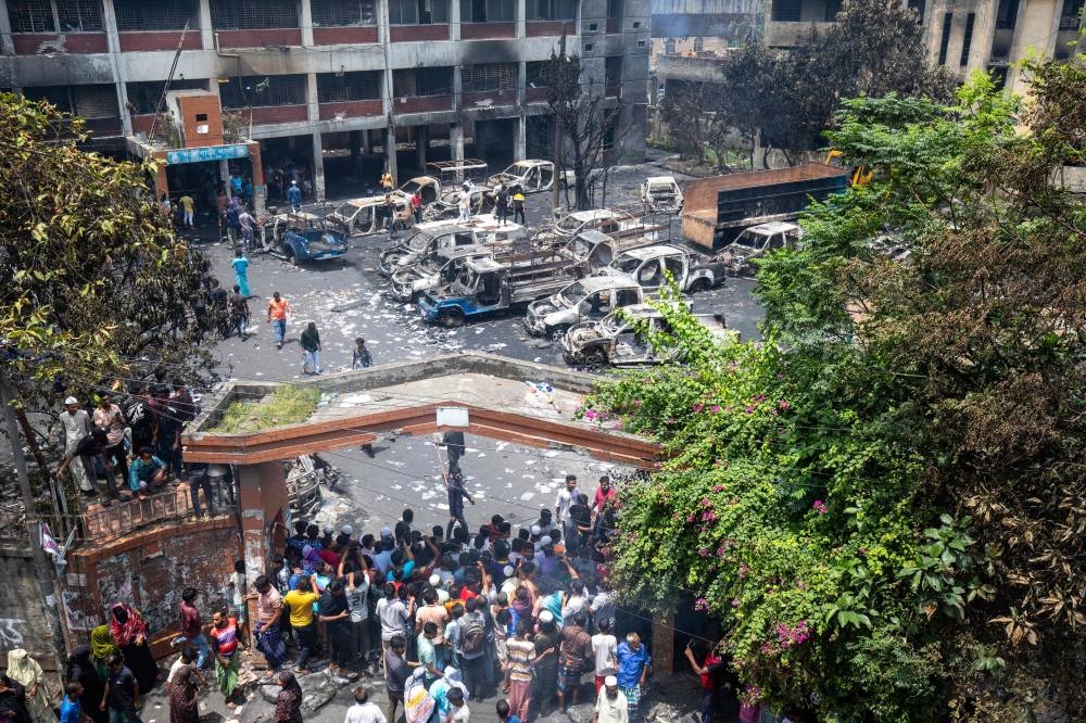 People gather to see burnt Jatrabari police station as anti-government protestors set fire in Dhaka on Tuesday, after former prime minister Sheikh Hasina fled the country. AFP