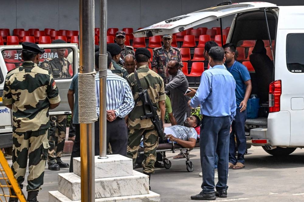 India's Border Security Force (BSF) personnel and other officials transfer Shahid Ali, an Indian citizen who got injured during yesterday's violence in Bangladesh, to an ambulance for further treatment at the India-Bangladesh border of Petrapole, about 100km north-east of Kolkata on Tuesday. AFP