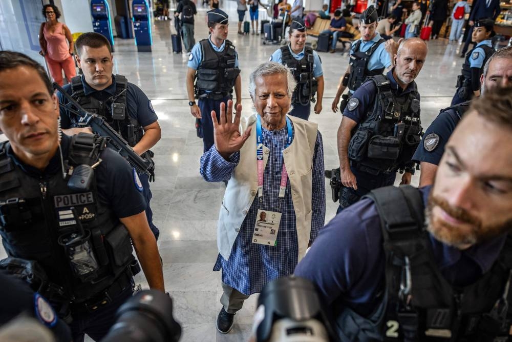 Bangladesh's finance pioneer Muhammad Yunus (C) is escorted by French police personnel as he arrives at Roissy-Charles de Gaulle Airport, north of Paris on Wednesday, enroute to Bangladesh, where he is set to lead a caretaker government after mass protests ousted premier Sheikh Hasina. AFP