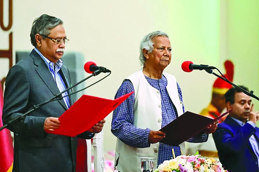 Nobel laureate Mohamed Yunus (centre) takes the oath of office as the chief adviser of Bangladesh’s new interim government during the oath-taking ceremony administered by President Mohamed Shahabuddin (left) in Dhaka yesterday.