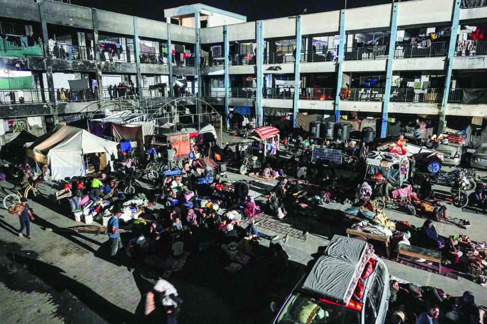 Displaced Palestinians prepare to spend the nigh in the courtyard of a UN school a in the southern Gaza Strip on Thursday 