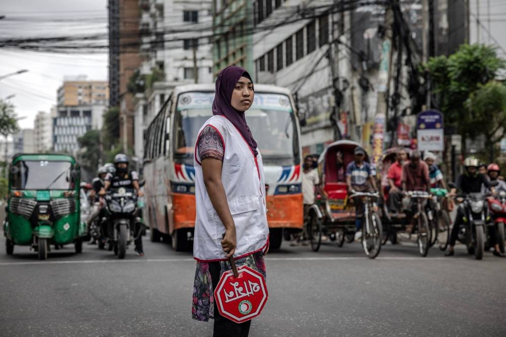 Commuters wait at a road crossing while Bangladeshi students control the traffic as police went on strike in Dhaka on Friday. AFP