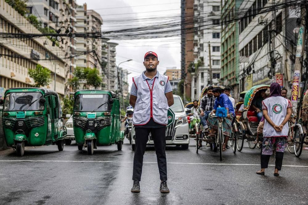 Commuters wait at a road crossing while Bangladeshi students control the traffic as police went on strike in Dhaka on Friday. AFP