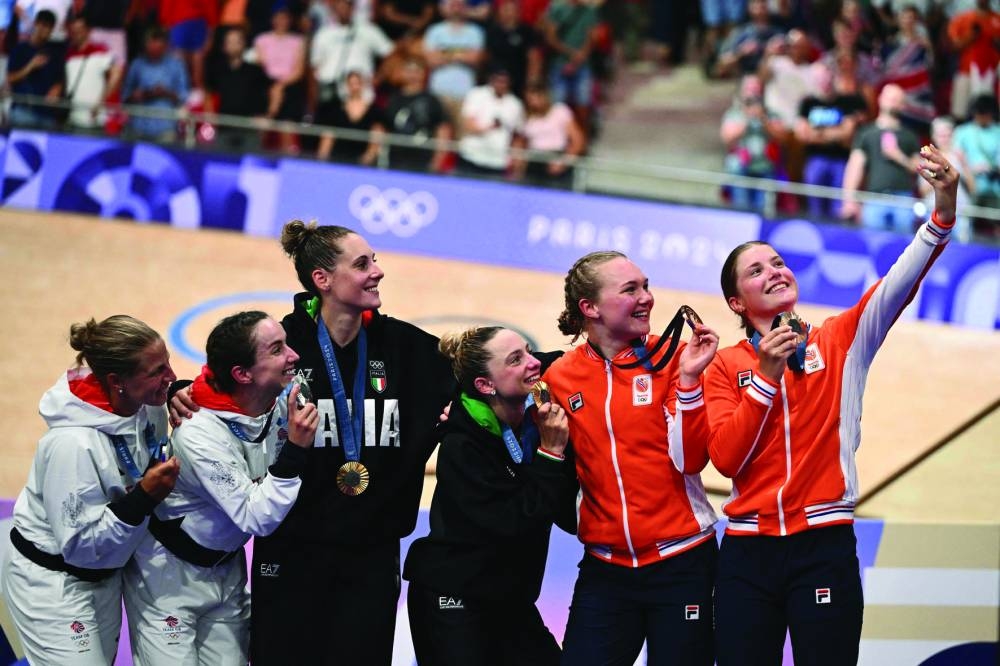 Gold medallists Italy’s Chiara Consonni and Vittoria Guazzini (centre), silver medallists Britain’s Elinor Barker and Neah Evans (left) and bronze medallists Netherlands’ Maike van der Duin and Lisa van Belle (right) pose for a selfie on the podium of the women’s track cycling madison event of the Paris 2024 Olympic Games at the Saint-Quentin-en-Yvelines National Velodrome in Montigny-le-Bretonneux, south-west of Paris, on Friday. (AFP)