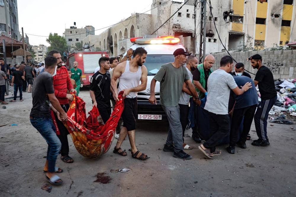 People remove the corpse of a person killed in an Israeli strike on a school in Gaza City on Saturday. AFP