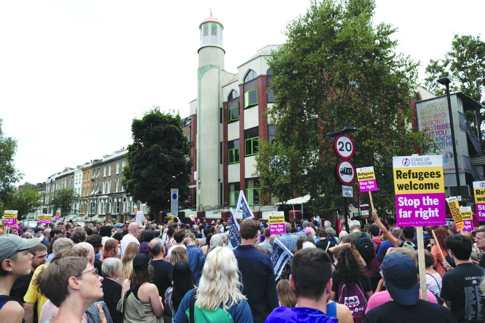 
People hold signs at a protest against racism outside Finsbury Park Mosque in London. 