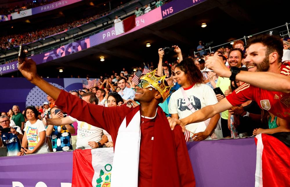 Mutaz Essa Barshim of Qatar celebrates with his national flag after winning bronze. REUTERS