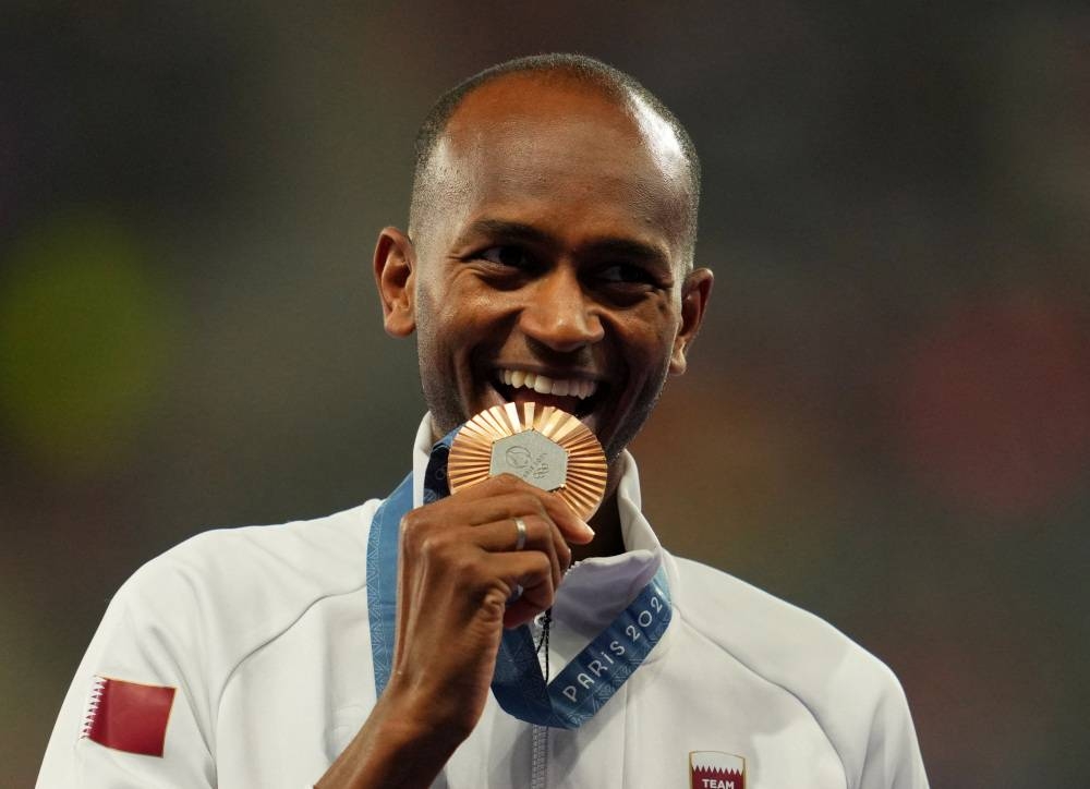 Bronze medallist Mutaz Essa Barshim of Qatar celebrates on the podium. REUTERS