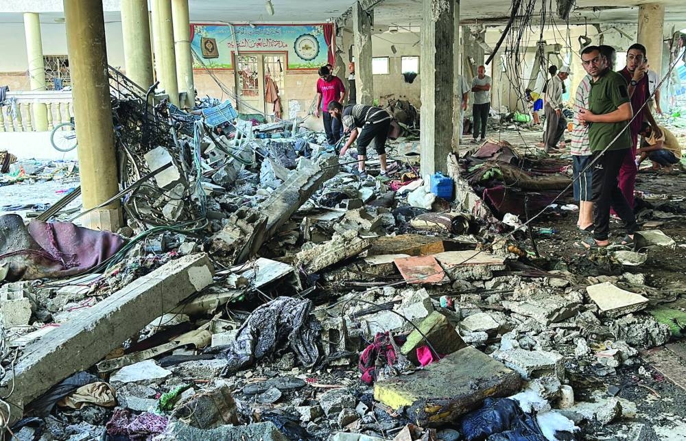 
Palestinians inspect the site of an Israeli strike on a school sheltering displaced people, in Gaza City, yesterday. 