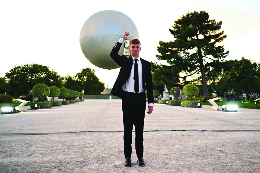 
French swimmer Leon Marchand takes the Olympic flame from the cauldron at the Jardin des Tuileries in Paris, before the start of the closing ceremony of the Paris Olympic Games. (AFP) 
