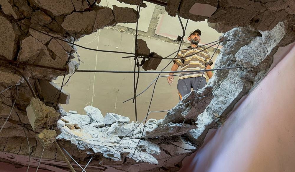 A Palestinian man inspects the site of an Israeli strike on a house in Gaza City Monday. REUTERS