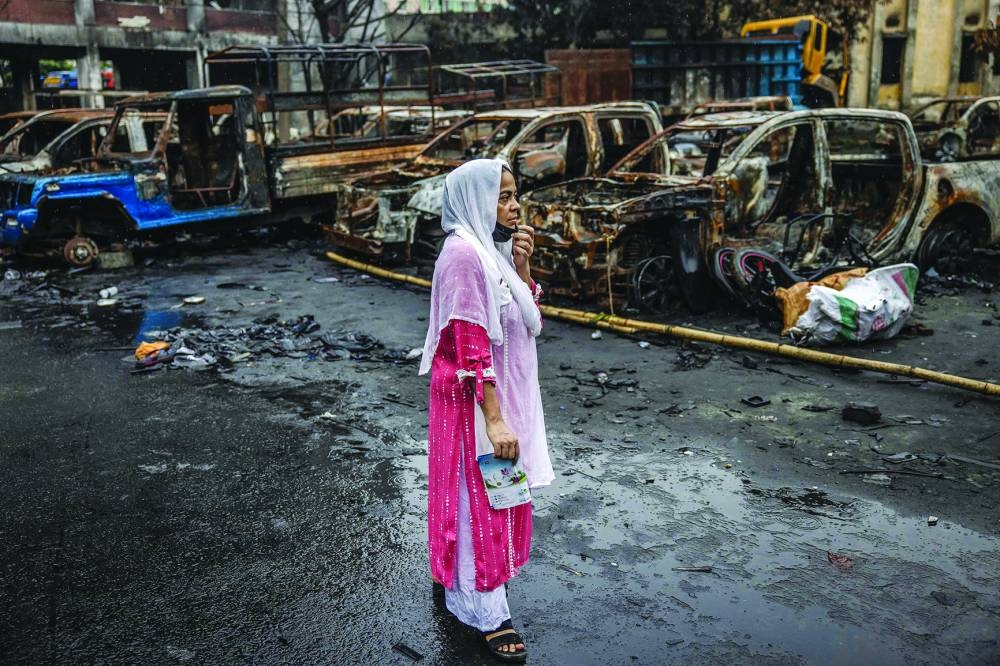 A woman stands in front of some police vehicles that were burned during anti-government demonstrations.