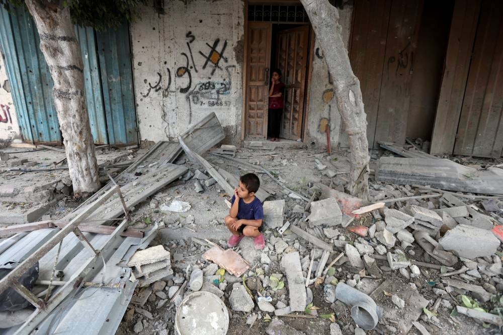 A Palestinian boy sits at the site of an Israeli strike on a house, amid the Israel-Hamas conflict, in Maghazi refugee camp in the central Gaza Strip, Wednesday. AFP