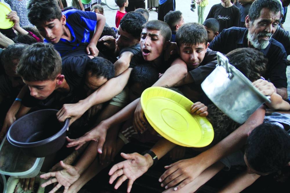 Palestinians react as they wait to receive food cooked by a charity kitchen, amid a hunger crisis in the northern Gaza Strip Wednesday.