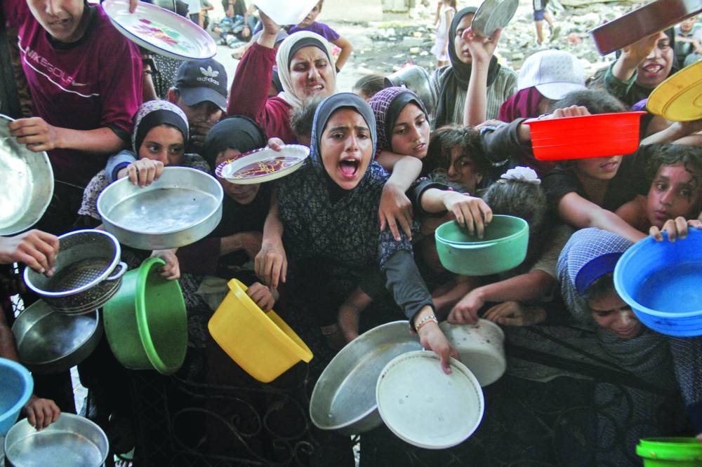 Palestinians react as they wait to receive food cooked by a charity kitchen, amid a hunger crisis in the northern Gaza Strip Wednesday.