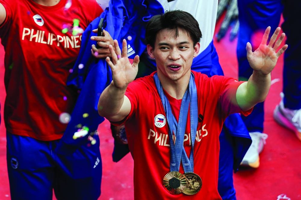 Filipino gymnast Carlos Edriel Yulo, who won gold in floor exercise and vault at the Paris Olympics, gestures during a welcome parade 
in Manila on Wednesday. (Reuters) 