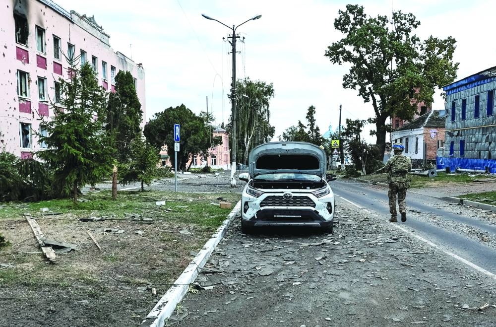 A Ukrainian serviceman patrols a street next to buildings, damaged during recent fighting between Ukrainian and Russian forces in controlled by Ukrainian army the town of Sudzha, Kursk region, Russia, on Friday. 