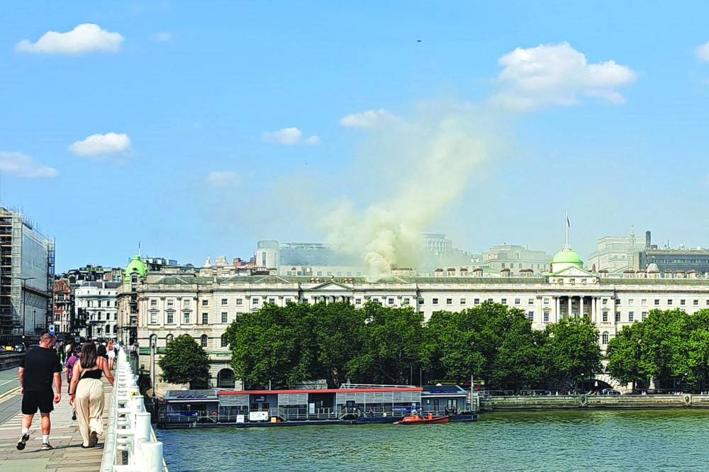 Viewed from Waterloo Bridge, smoke is seen rising into the sky from a fire located in the roof of Somerset House beside the River Thames in London.