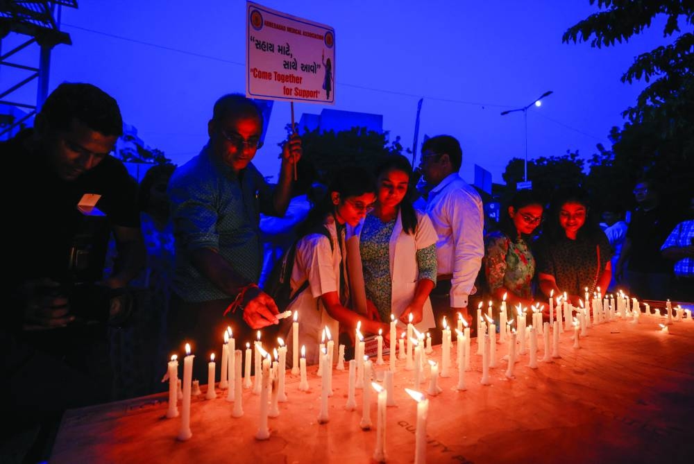 
Doctors light candles to pay homage to a victim of rape and murder, who was a a trainee medic at a hospital in Kolkata, in Ahmedabad. 