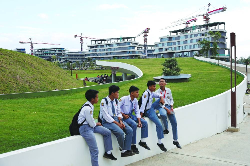 
Students sit at a park near office buildings in Nusantara. 