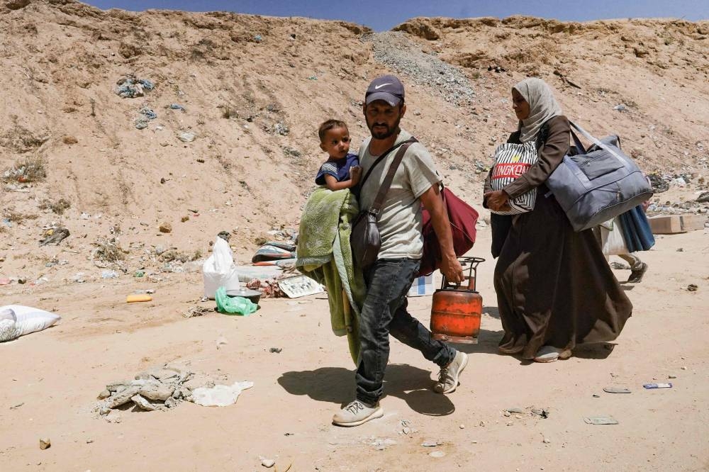 Palestinians carry their belongings as they flee a makeshift camp for displaced people in Khan Younis in the southern Gaza Strip after Israeli tanks took position on a hill overlooking the area on Sunday 