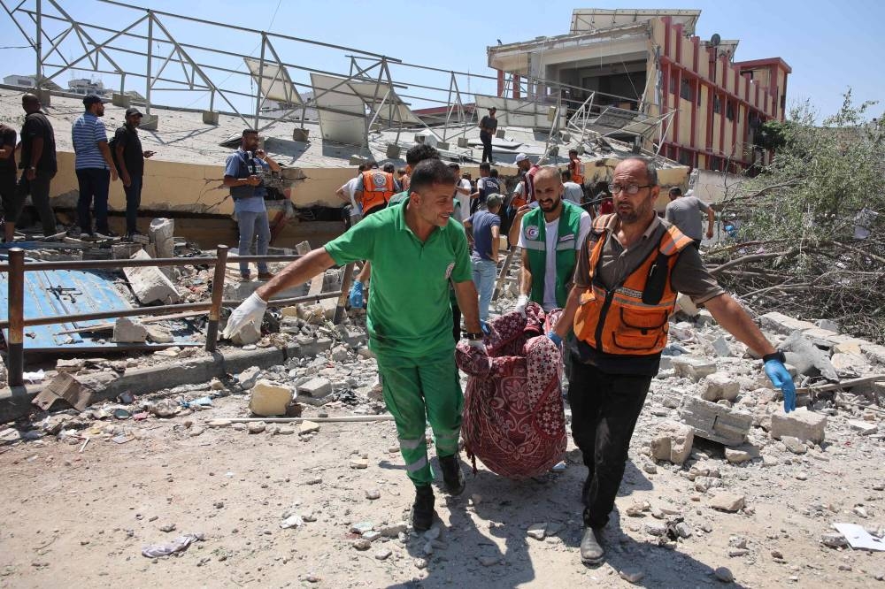 Paramedics carry a body from the site of an Israeli strike on a school, housing displaced Palestinians, in the Rimal neighbourhood of central Gaza City on Tuesday. AFP