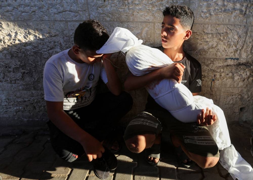 A cousin of a Palestinian child killed in an Israeli strike holds the body in Deir Al-Balah in the central Gaza Strip, Tuesday. REUTERS