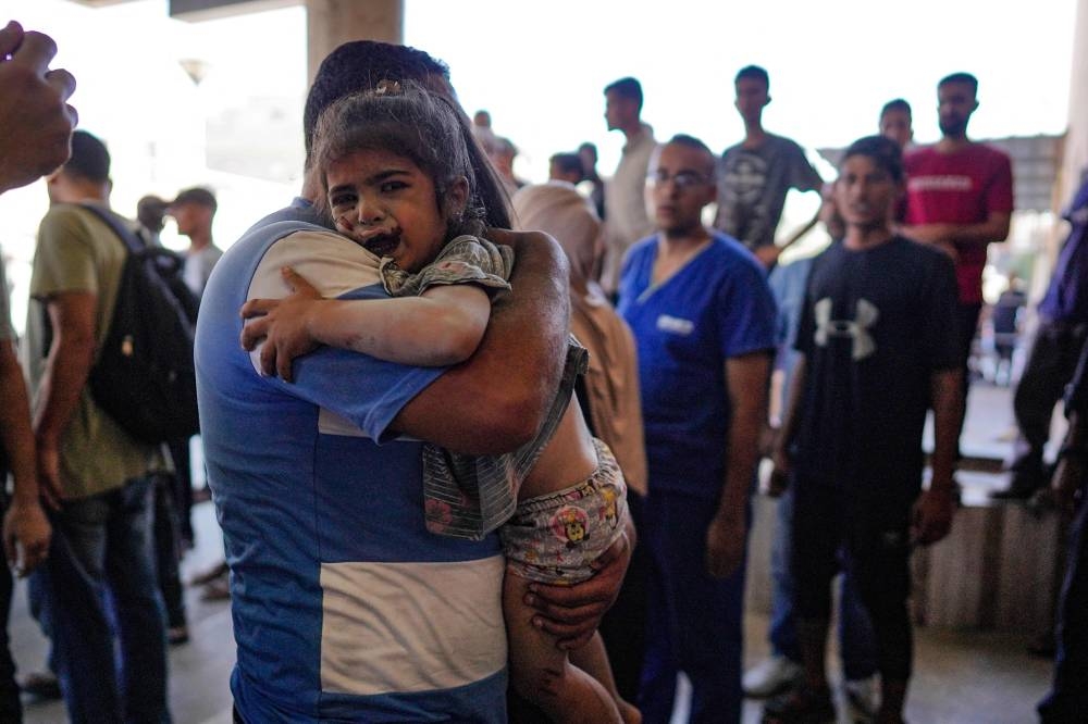 A Palestinian child injured in an Israeli strike reacts as she's carried to the Nasser Medical Complex in Khan Yunis in the southern Gaza Strip on Wednesday. AFP