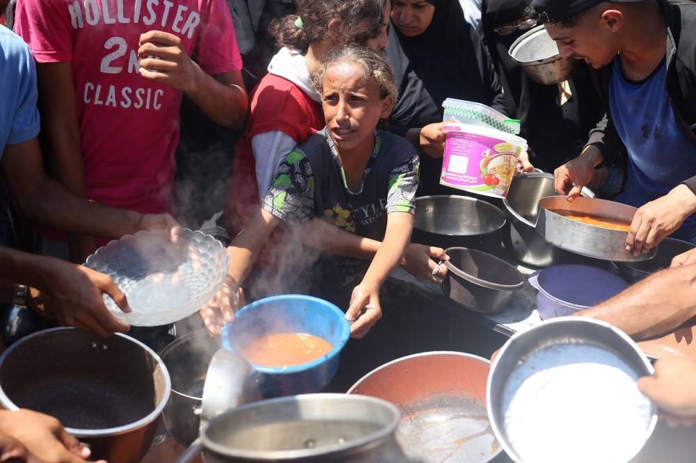 Palestinians queue to receive a meal during food distribution in Bureij refugee camp central of Gaza Strip on Wednesday. AFP