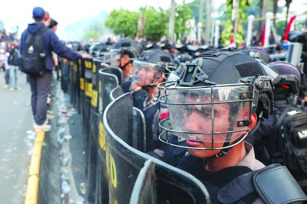 Riot police stand in line outside the Indonesian parliament building in Jakarta as protesters rally against planned revisions to the country’s election law. – Reuters