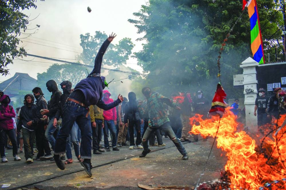 Demonstrators throw stones at the police outside the parliament building in Bandung, West Java. – AFP