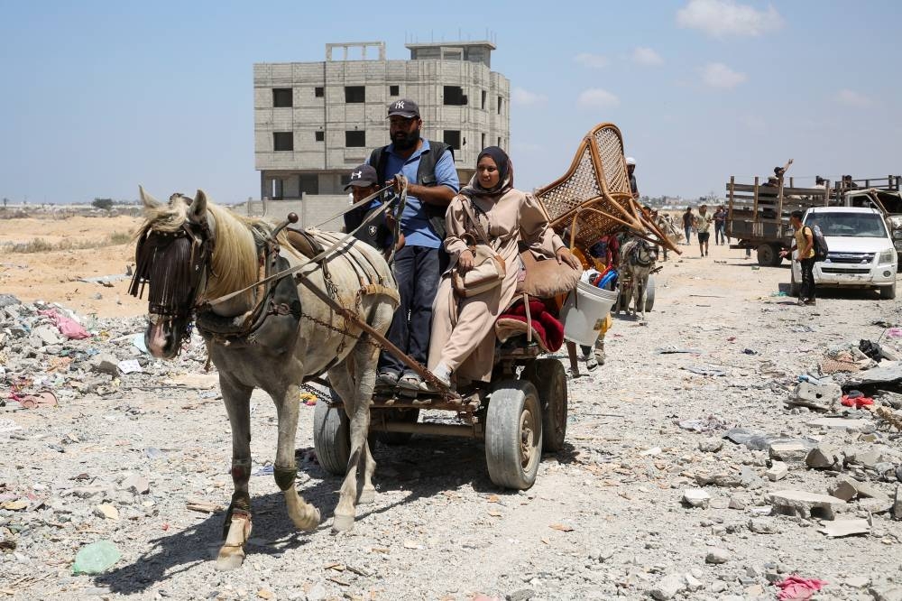 Palestinians ride an animal-drawn cart loaded with belongings in Hamad City, following an Israeli raid, in Khan Younis, in the southern Gaza Strip, on Saturday. REUTERS