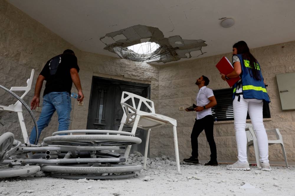 Official property surveyors assess the damage to a residential building following a direct-hit from a projectile, after Hezbollah launched hundreds of rockets and drones towards Israel, in northern Israel on Sunday. REUTERS